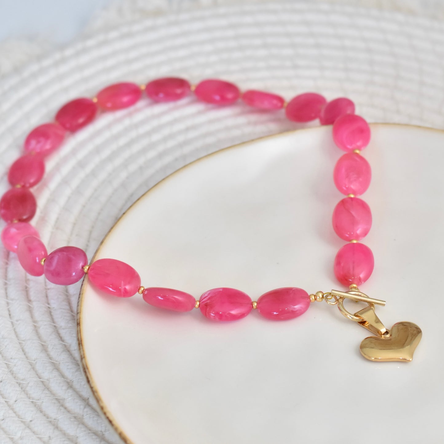 Ovale fuchsia kralen ketting met hart bedel - goudkleurig