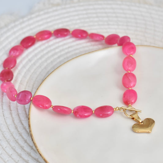 Ovale fuchsia kralen ketting met hart bedel - goudkleurig