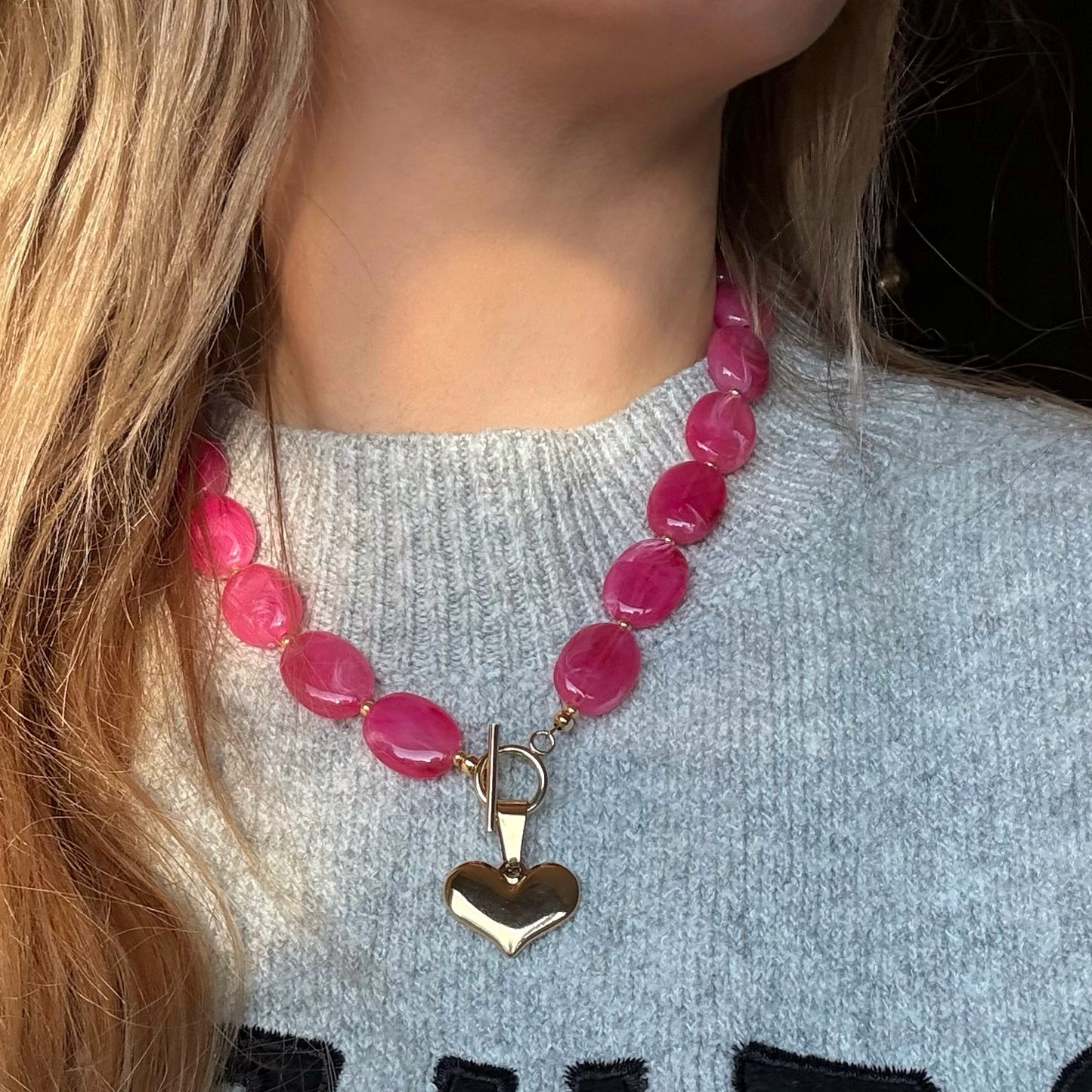 Ovale fuchsia kralen ketting met hart bedel - goudkleurig