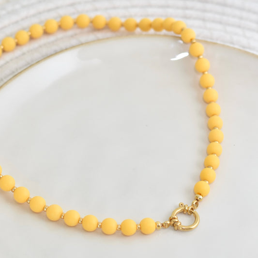 Okergele kralen ketting met gouden accenten en boeislot